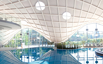 Blick auf das Becken und das elegante Dachdesign der Therme